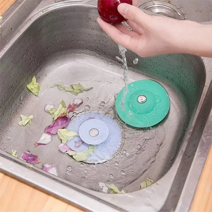 Deux bouchons Bigbon dans un évier en inox, l'eau passe et les déchets restent dessus